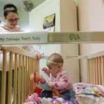 A mother watches over her daughter as she plays in her crib inside her room at a correctional facility.