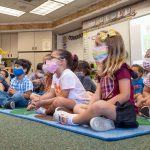 Students listen to their teacher during their first day of kindergarten.