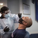 A health care worker use a nasal swab to test a patient for COVID-19.