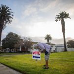 A woman arranges a voting sign near the Main Street Branch Library vote center in the early morning.