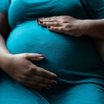 Pregnant woman touching her belly.
