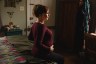 Sara Toups sits on a bed and holds her pregnant belly at her home.
