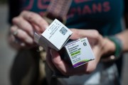 A person holds boxed testosterone prescriptions.