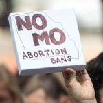 A hand holding a small white sign that reads 